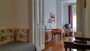 Una sala de estar con un sofá, una mesa, un televisor y un comedor.