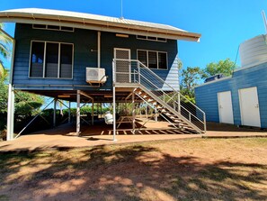 A two-story house with a covered porch, a staircase, and a water tank.
