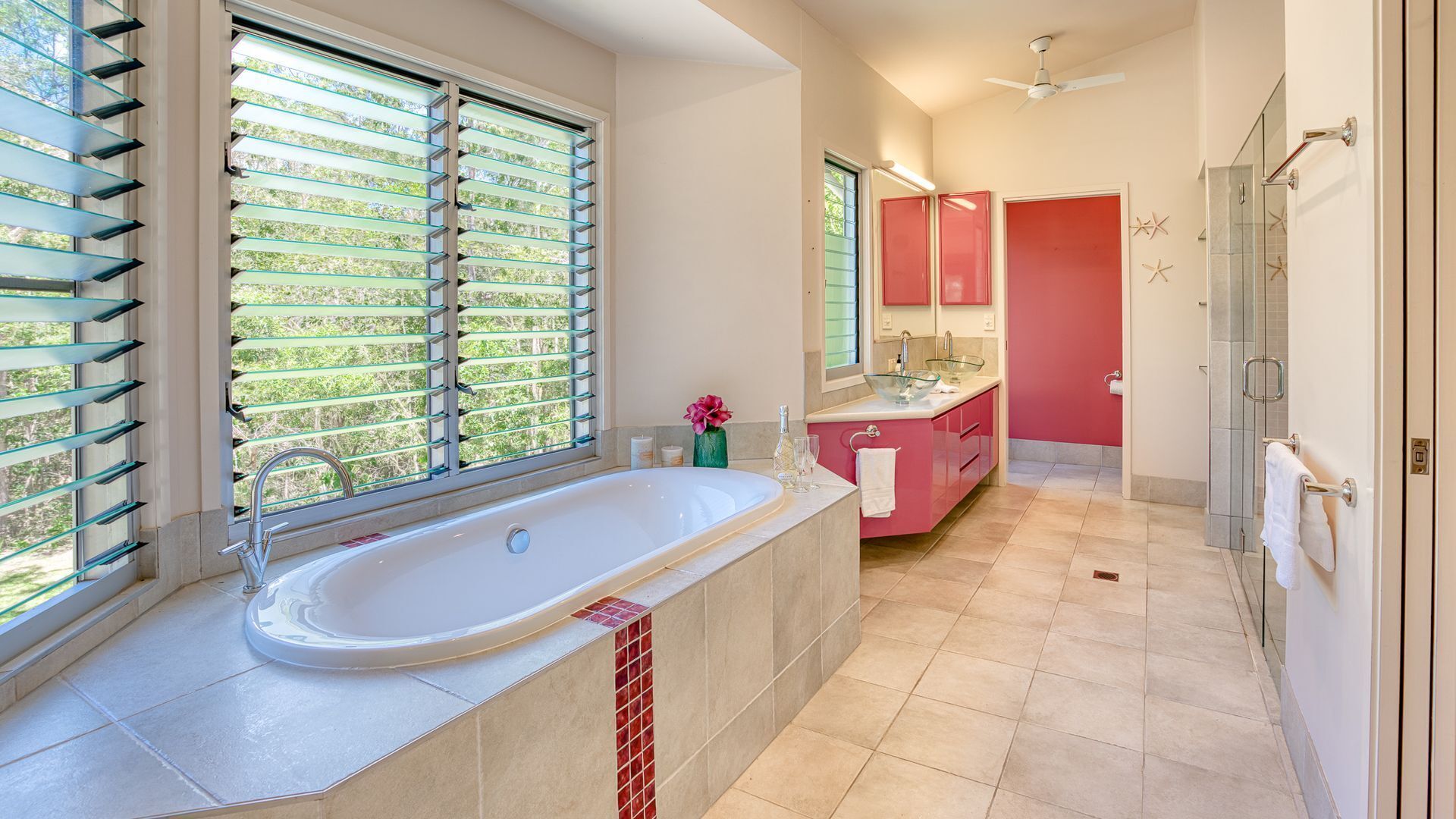 Une salle de bain moderne avec une baignoire sur pieds, une douche à parois de verre et un meuble-lavabo doté d’un meuble rouge.