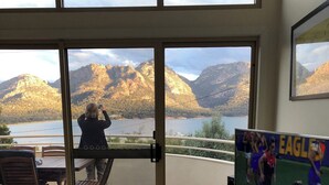 A room with a large sliding glass door leading to a balcony with a mountain view.