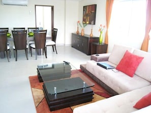 A modern living room with a sofa, coffee table, and dining area.