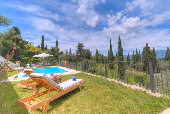 Una piscina al aire libre, sillones reclinables de piscina