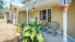 Une maison avec une véranda, une chaise berçante et une plante en pot.