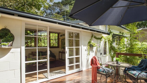 Une terrasse couverte avec un plancher en bois, une table avec des chaises et un grand parasol.
