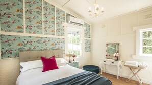 Une chambre à coucher avec un lit, une table de chevet, une commode, un miroir et une fenêtre.