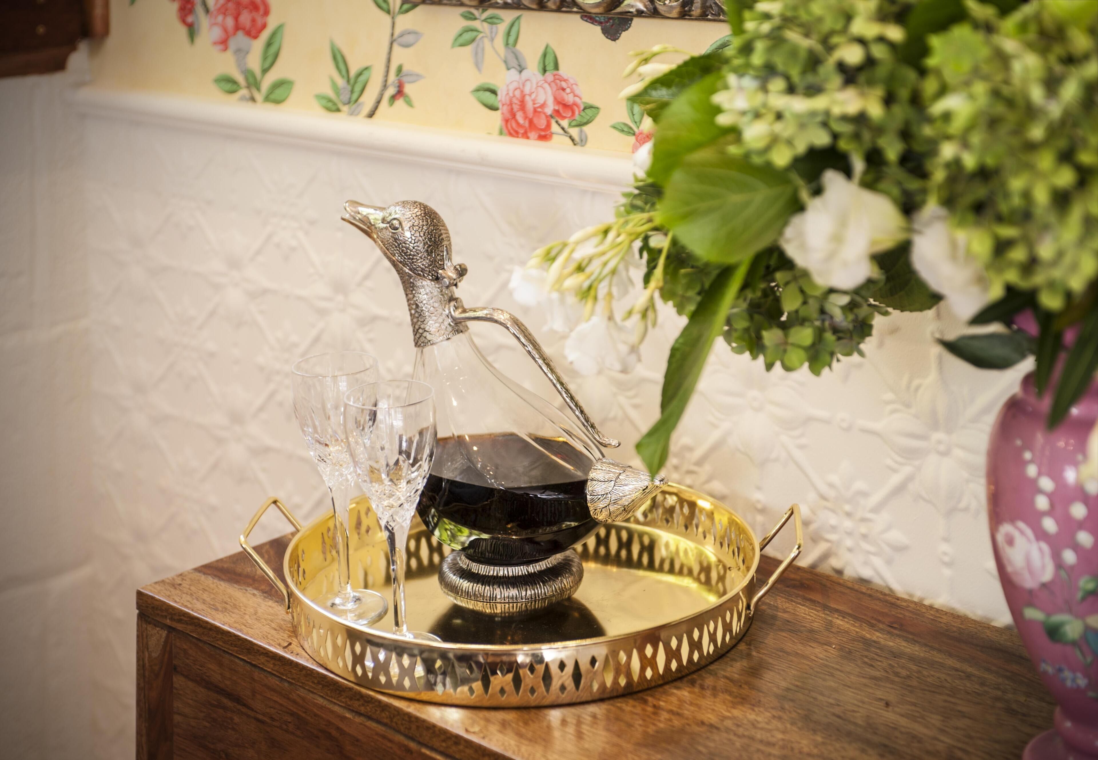 A tray with a decorative pitcher and glasses on a wooden table.