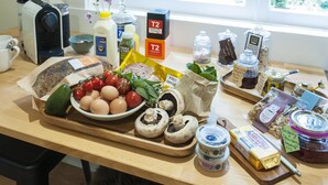 Un plan de travail de cuisine avec divers aliments, notamment des œufs, des tomates, des champignons et des pots de confitures.