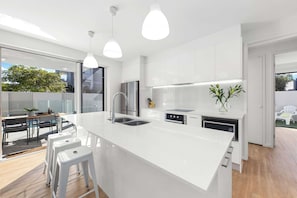 Una cocina moderna con una isla grande, electrodomésticos de acero inoxidable e iluminación colgante.