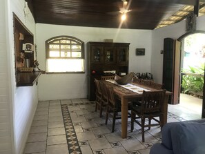 Uma área de refeições com uma mesa e cadeiras de madeira, um armário com portas de vidro e um chão estampado.