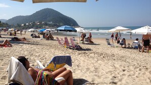 A beach with umbrellas, chairs, and people relaxing. - Beach house with lots of greenery, a true beach country house.<br> 24-hour security. (Guarujá)