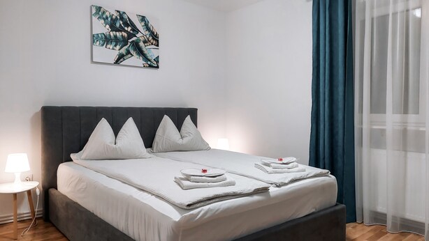 A neatly made bed with pillows, a bedside lamp, and a wall art piece. - Apartment Alina Deva (Deva)