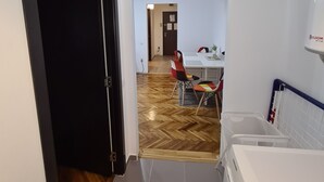 A laundry area with a washing machine, a drying rack, and a small table with chairs. - Apartment Alina Deva (Deva)