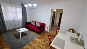 A modern living room with a red sofa, a white coffee table, and a herringbone wood floor. - Apartment Alina Deva (Deva)