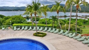 A pool area with lounge chairs and a view of the sea. - Oceanview Studio Apartment w/ Community Pool & Views of Flamingo Marina (Playa Flamingo)