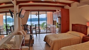 A hotel room with a balcony, a desk, a bed, and a TV. - Oceanview Studio Apartment w/ Community Pool & Views of Flamingo Marina (Playa Flamingo)