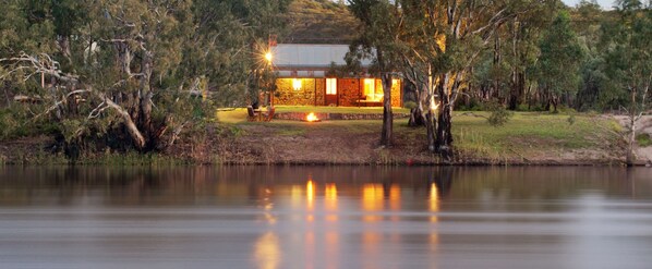 A lakeside lodge with stone walls, a fire pit, and a dining area.