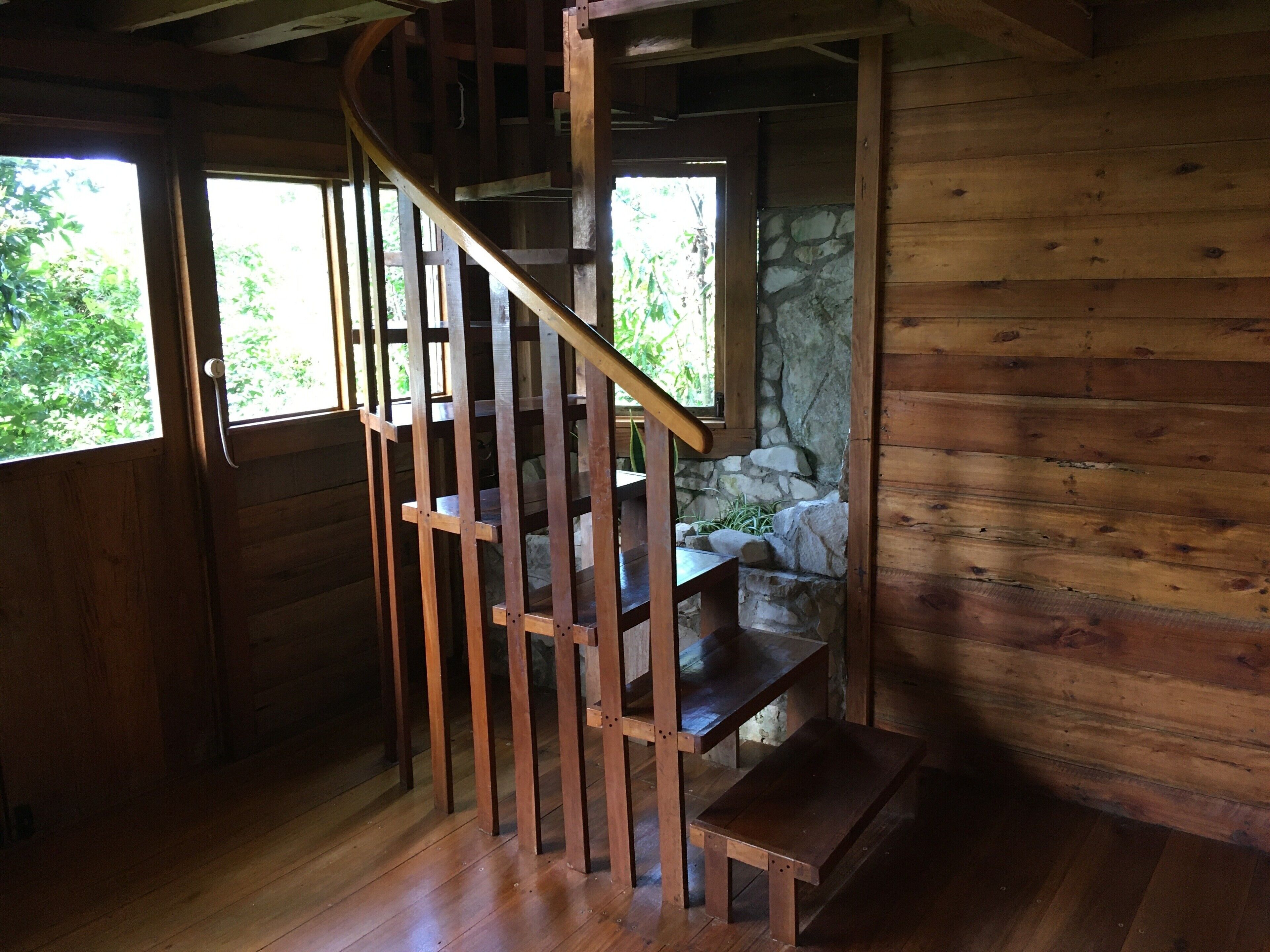 A wooden staircase with a stone wall behind it, leading to a higher level.