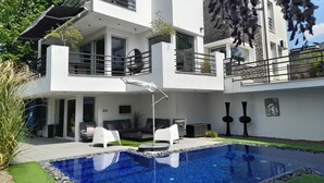 A modern two-story house with a swimming pool, outdoor seating, and a balcony. - PRIVATE Family VILLA with jakuzzi & swimming pool (Budaörs)
