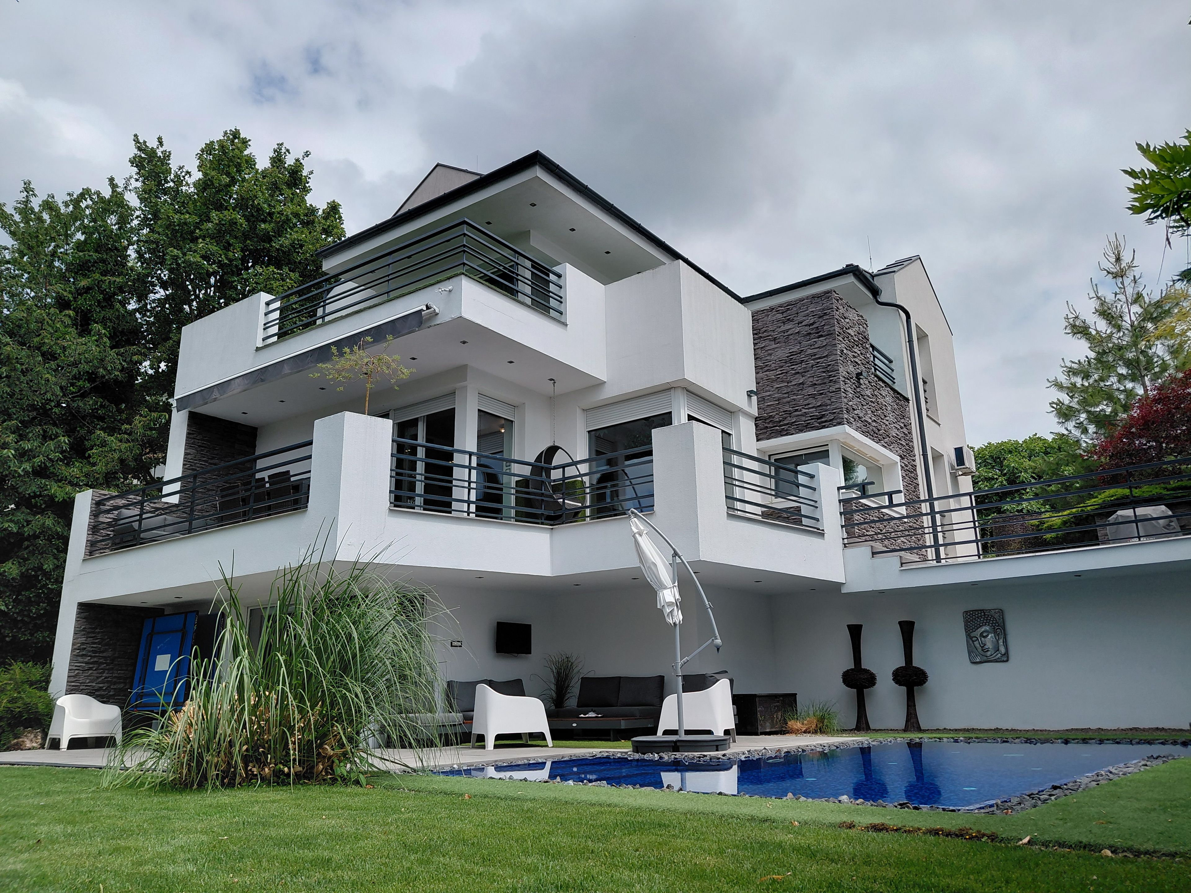 Une maison moderne à deux étages, dotée d’une piscine, d’un espace extérieur aménagé et d’une pelouse bien entretenue.