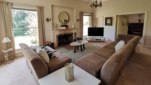 A living room with a fireplace, sofa, TV, and a chandelier. - Lake House Benalla-  Late Sunday checkout available upon request (Benalla)