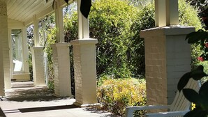 A covered outdoor seating area with white plastic chairs and a brick pillar. - Lake House Benalla-  Late Sunday checkout available upon request (Benalla)