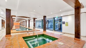 A modern indoor pool area with a central hot tub, surrounded by exercise equipment and a glass wall. - Harbourside Comfort and Charm (Pyrmont)