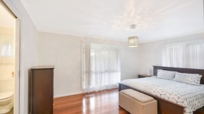 Ein Schlafzimmer mit einem hölzernen Bett, einer Sitzbank, einem Nachttisch und einer Deckenleuchte.