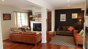 Una sala de estar con chimenea, un sofá, una mesita de centro y una alfombra estampada.