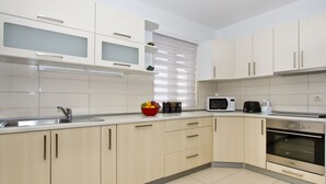A modern kitchen with light-colored cabinets, a stainless steel sink, a microwave, and an oven. - Panoramic view, swimming pool, 9 bedrooms, fitness,  7 bathrooms, 16 persons (Omiš)