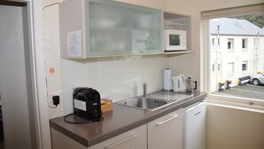 Eine kleine Küche mit Mikrowelle, Kaffeemaschine und Blick auf die Straße durch ein Fenster.