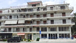 Un immeuble à plusieurs étages doté de balcons, avec une entrée au niveau du sol et un panneau bleu indiquant un passage piéton.