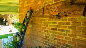 A brick wall with a sign reading "Melaeuca Cottage". - Romantic luxury close to town, fine food dining and wineries. EV charger. (Orange)