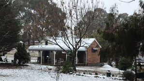 A snow-covered landscape with a brick building featuring a porch and a covered area. - Romantic luxury close to town, fine food dining and wineries. EV charger. (Orange)