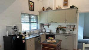 A compact kitchen with a refrigerator, coffee maker, and a small dining table. - Romantic luxury close to town, fine food dining and wineries. EV charger. (Orange)