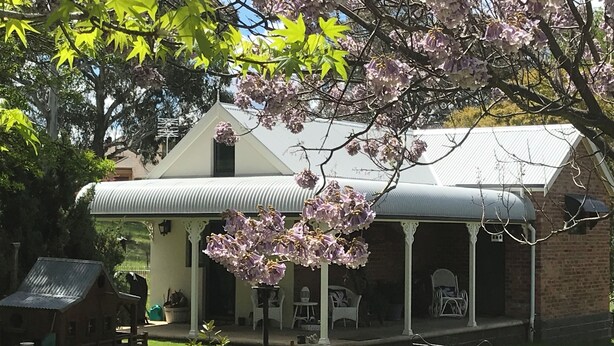 A house with a covered porch, a small garden, and a birdhouse. - Romantic luxury close to town, fine food dining and wineries. EV charger. (Orange)