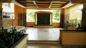 Amplo espaço interno com lareira de pedra, escada e plantas em vasos.