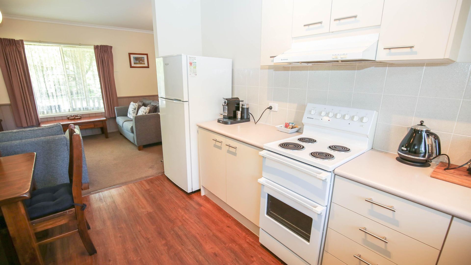 A compact kitchen with a white stove, a coffee maker, and a refrigerator.