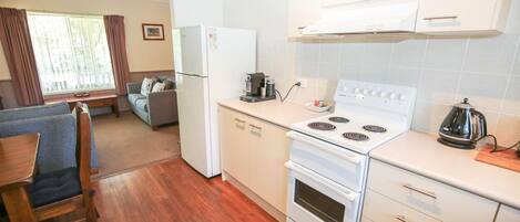 A compact kitchen with a white stove, a coffee maker, and a refrigerator.