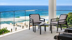 Enjoy ocean views from this balcony with a teapot and cups on a small table, perfect for a relaxing moment.