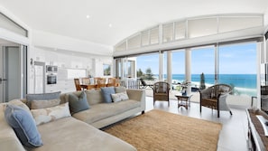 Relax in this open-plan living space with a comfortable sofa set, dining table, and wicker seating area.