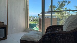 A balcony with wicker furniture, a television, and a view of a residential area with palm trees.