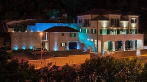 Un immeuble à plusieurs étages doté d’une piscine, d’un espace extérieur aménagé et d’une voiture garée devant.