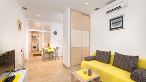 Un salon moderne avec un canapé jaune, une table basse et une porte coulissante donnant sur la cuisine.