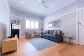Ein Wohnzimmer mit einer Couch, Sesseln, einem kleinen Tisch, einem Kamin und einem Deckenventilator.