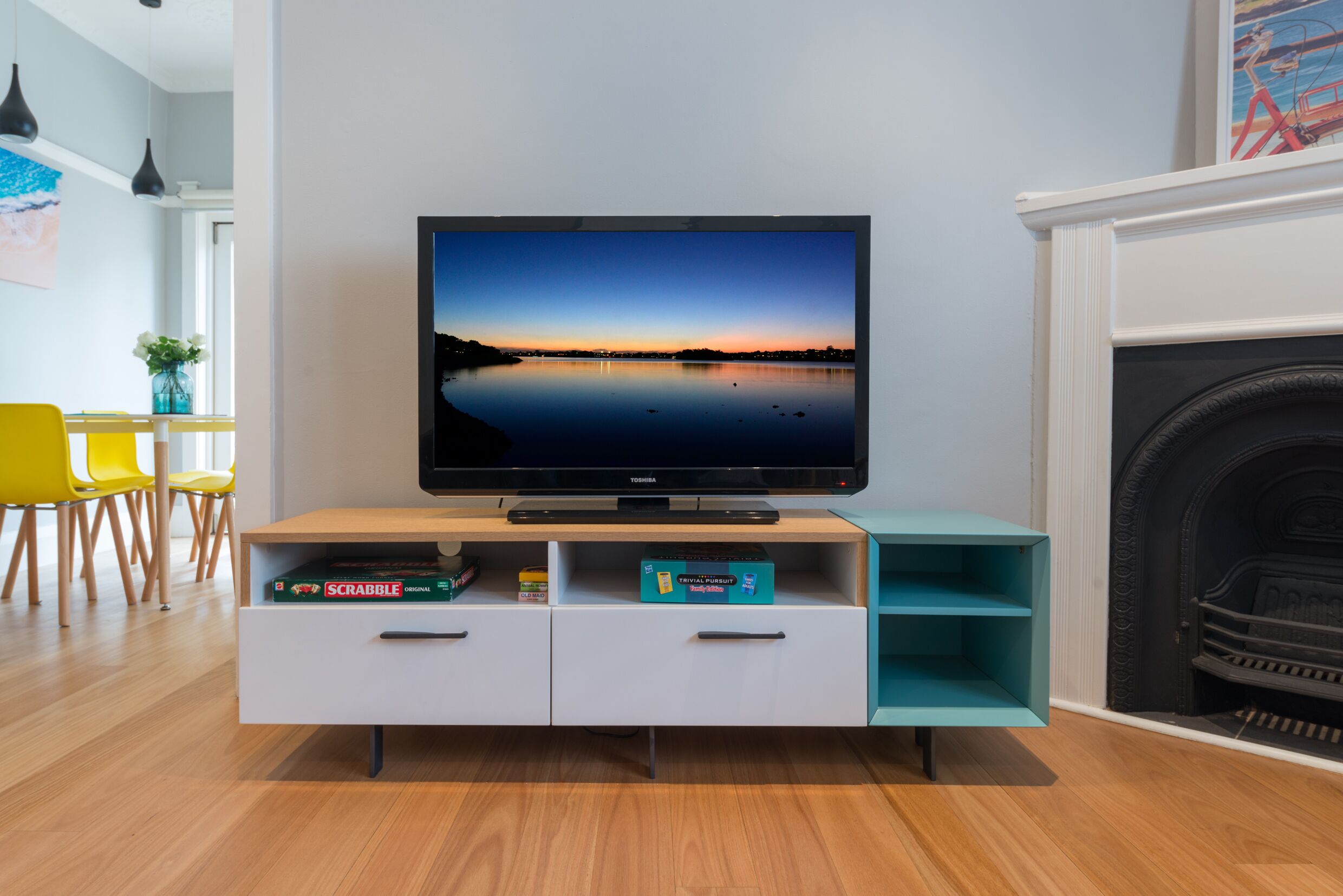 Ein Flachbildfernseher auf einem Holz-TV-Möbel mit Blick auf einen See und einen Sonnenuntergang.