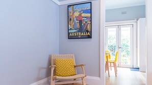 Ett rum med en flätstol, en inramad bild av Australien och utsikt mot omvärlden.