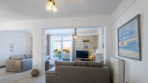 En moderne stue med en beige sofa, et fjernsyn og en stenvæg.