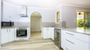 Una cocina moderna con armarios blancos, microondas, horno y lavavajillas.