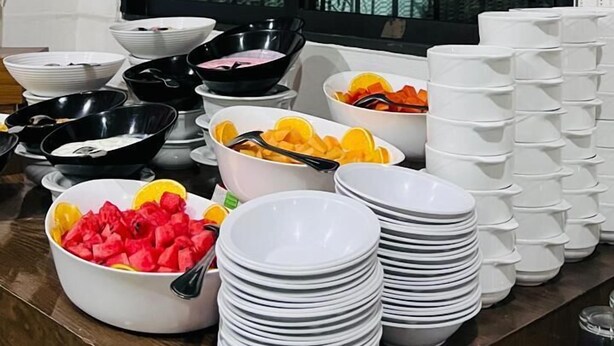 A buffet setup with various dishes and stacked plates. - Hotel San Lucas (Mexico City)