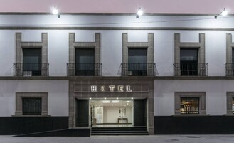 A hotel facade with a clear entrance, multiple windows, and a balcony on the upper floor.